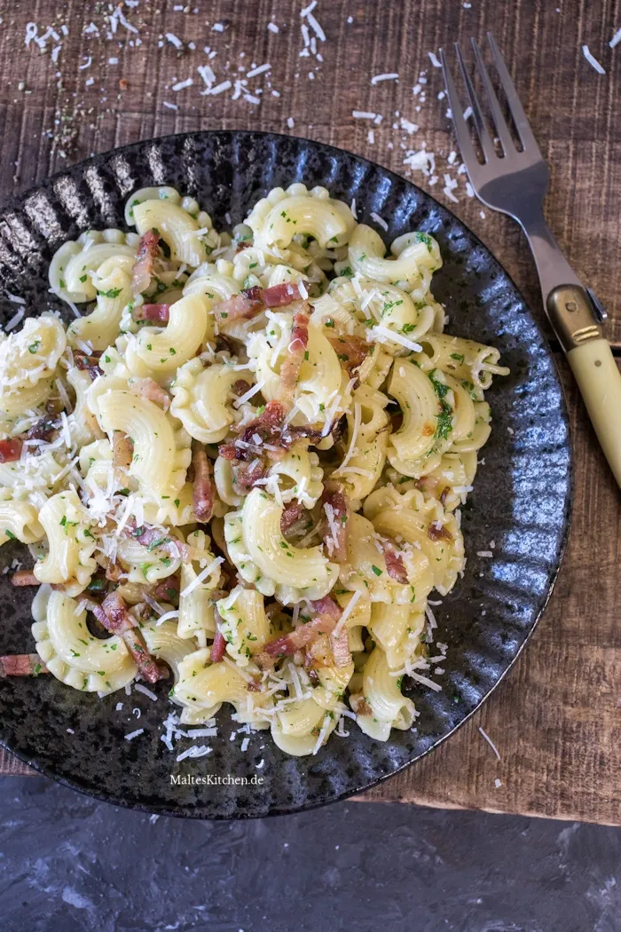 Nahaufnahme von Pasta mit knusprigem Pancetta, roten Zwiebeln, Knoblauch und frischem Parmesan.