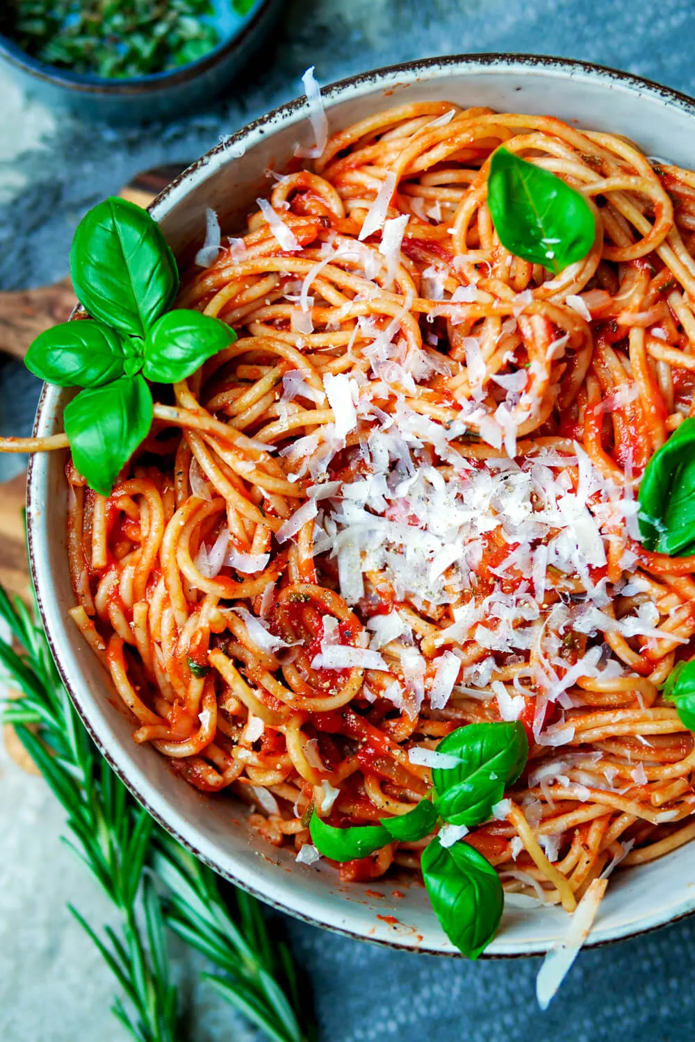 Nahaufnahme von Spaghetti mit Tomatensoße, garniert mit frisch geriebenem Parmesan und Basilikum