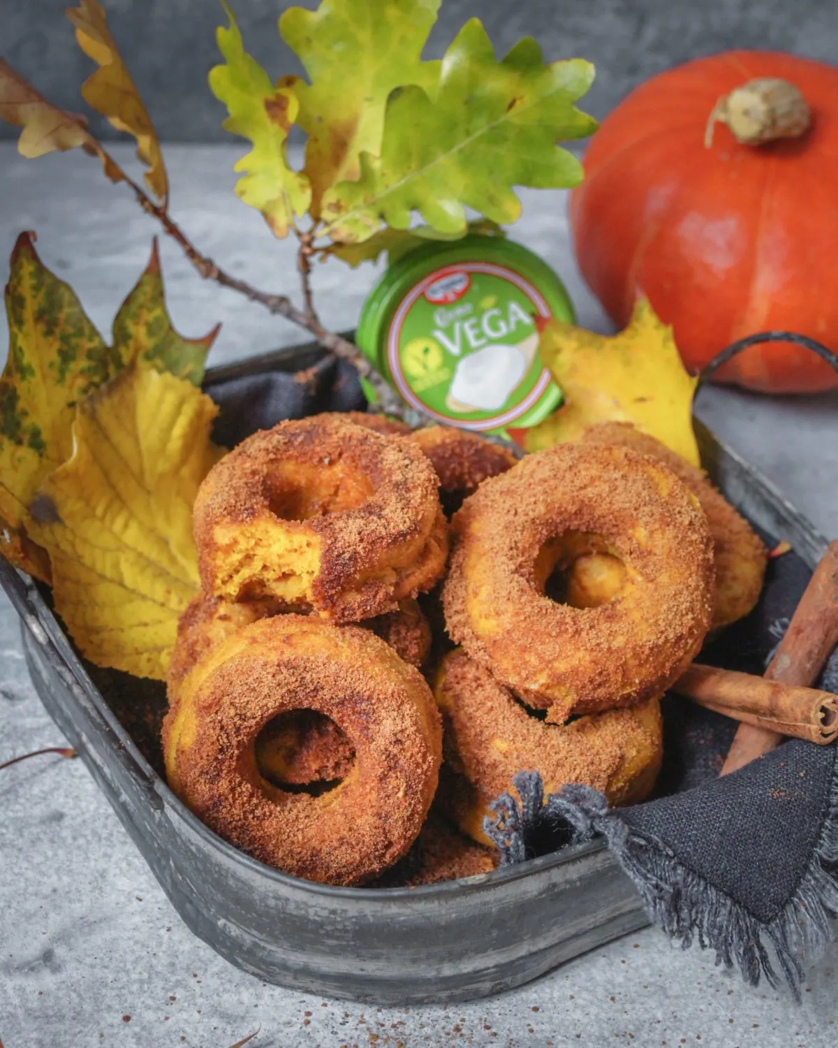 Nahaufnahme von veganen Kürbis-Donuts, verziert mit Zimtzucker und frischer Zitronenglasur