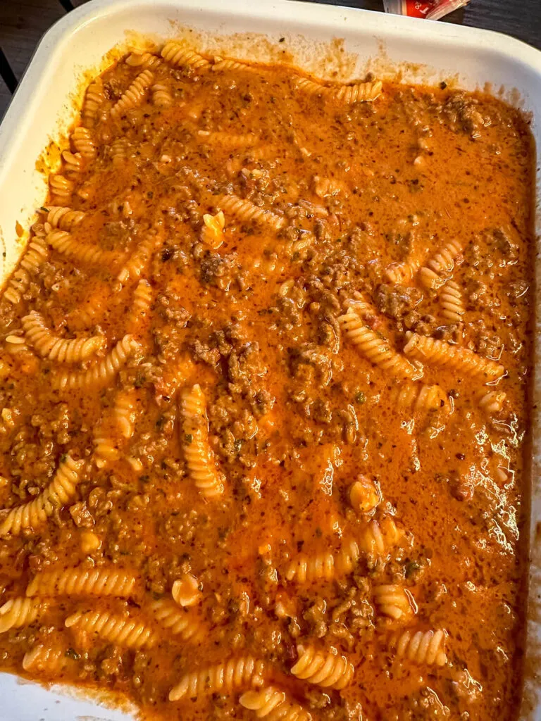 Nudel-Hackfleisch-Auflauf in einer Auflaufform, kurz bevor der Käse zum Überbacken hinzugefügt wird.