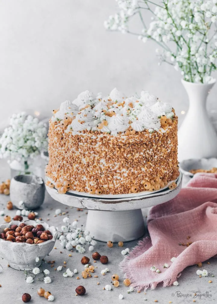 Nusstorte mit Sahne, gehackten Haselnüssen und weißen Johannisbeeren