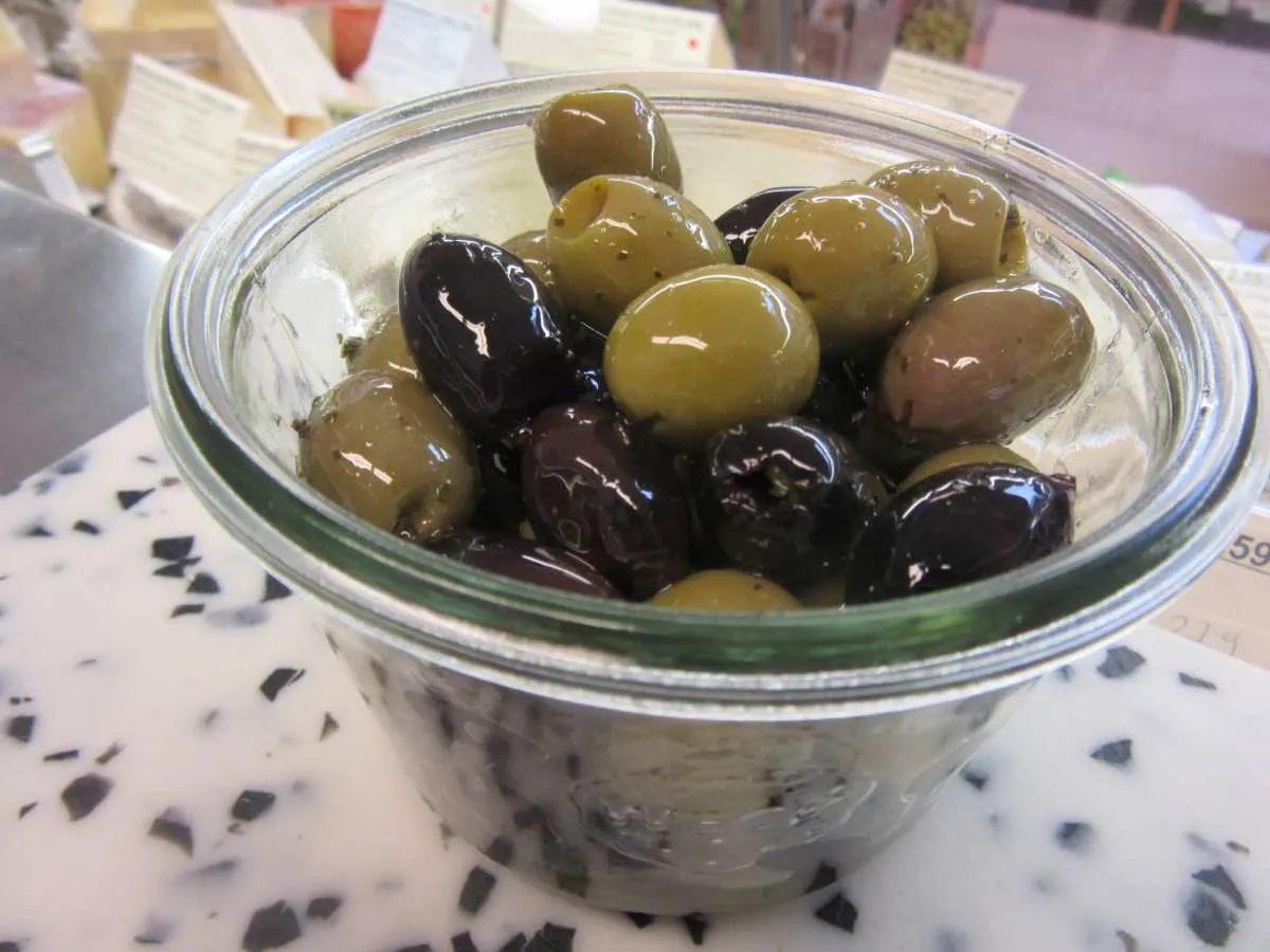 Oliven in wiederverwendbaren Behältern, ein Symbol für Nachhaltigkeit, die auch in der Produktion von Schedel Backwaren geschätzt wird.