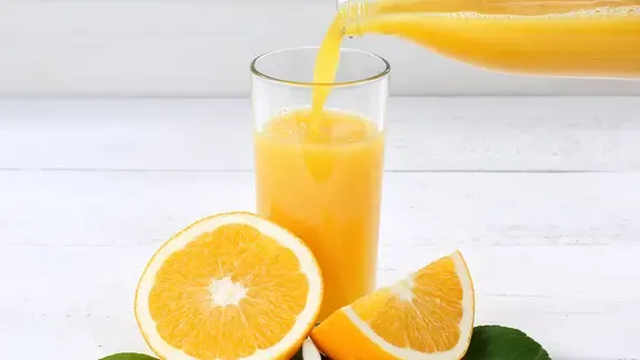 Orangensaft wird in ein Glas gegossen