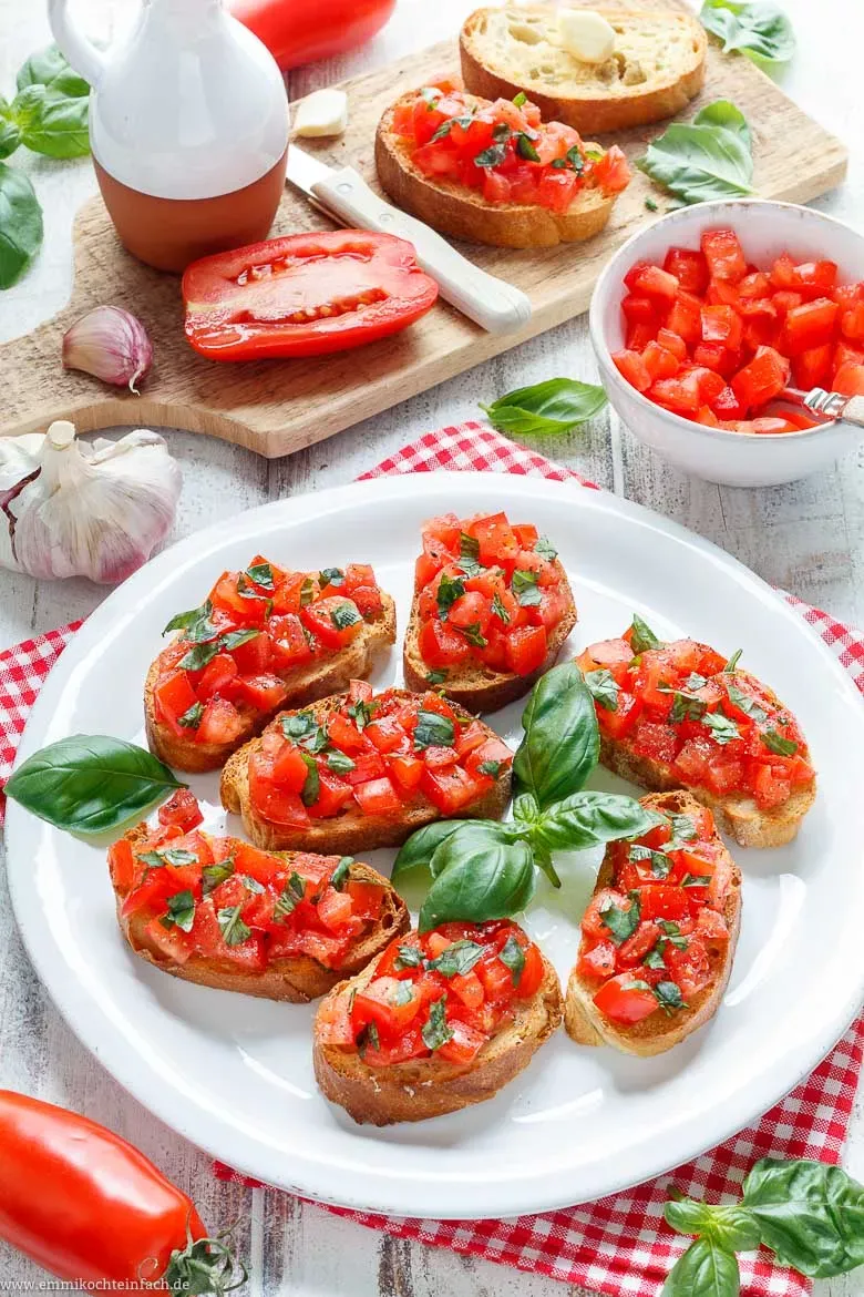 Original Bruschetta Rezept mit Tomaten, servierfertig auf einem Holzbrett.