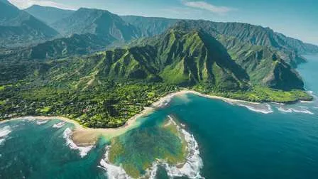 Panoramablick aus der Vogelperspektive auf die grüne, zerklüftete Küste der hawaiianischen Insel Kauai, mit üppigen Regenwäldern und steilen Klippen.