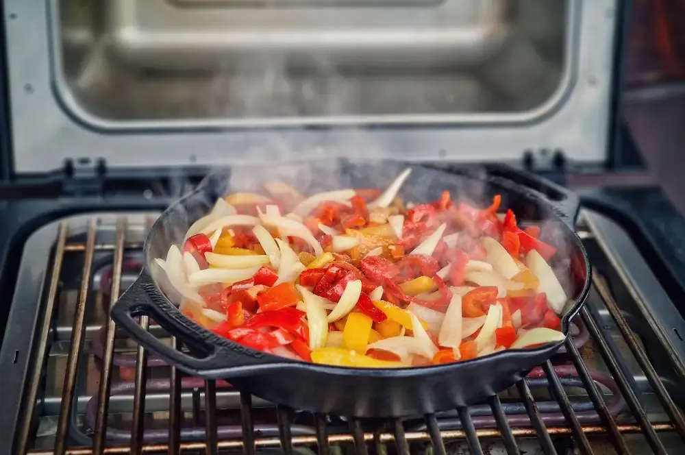 Paprika- und Zwiebelstreifen werden in einer gusseisernen Pfanne auf dem Severin SEVO Elektrogrill für das Letscho Rezept angeröstet.