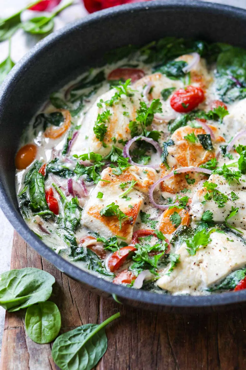 Parmesan-Hähnchen mit Spinat und Soße in einer Pfanne, servierfertig