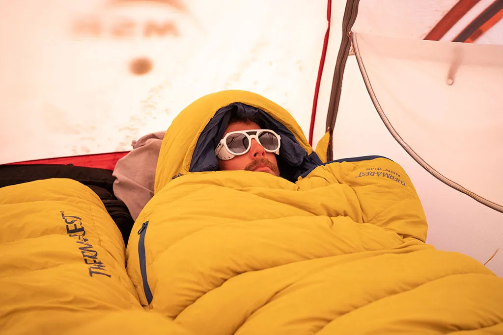 Person entspannt in einem warmen Schlafsack im Zelt, Blick auf die Natur