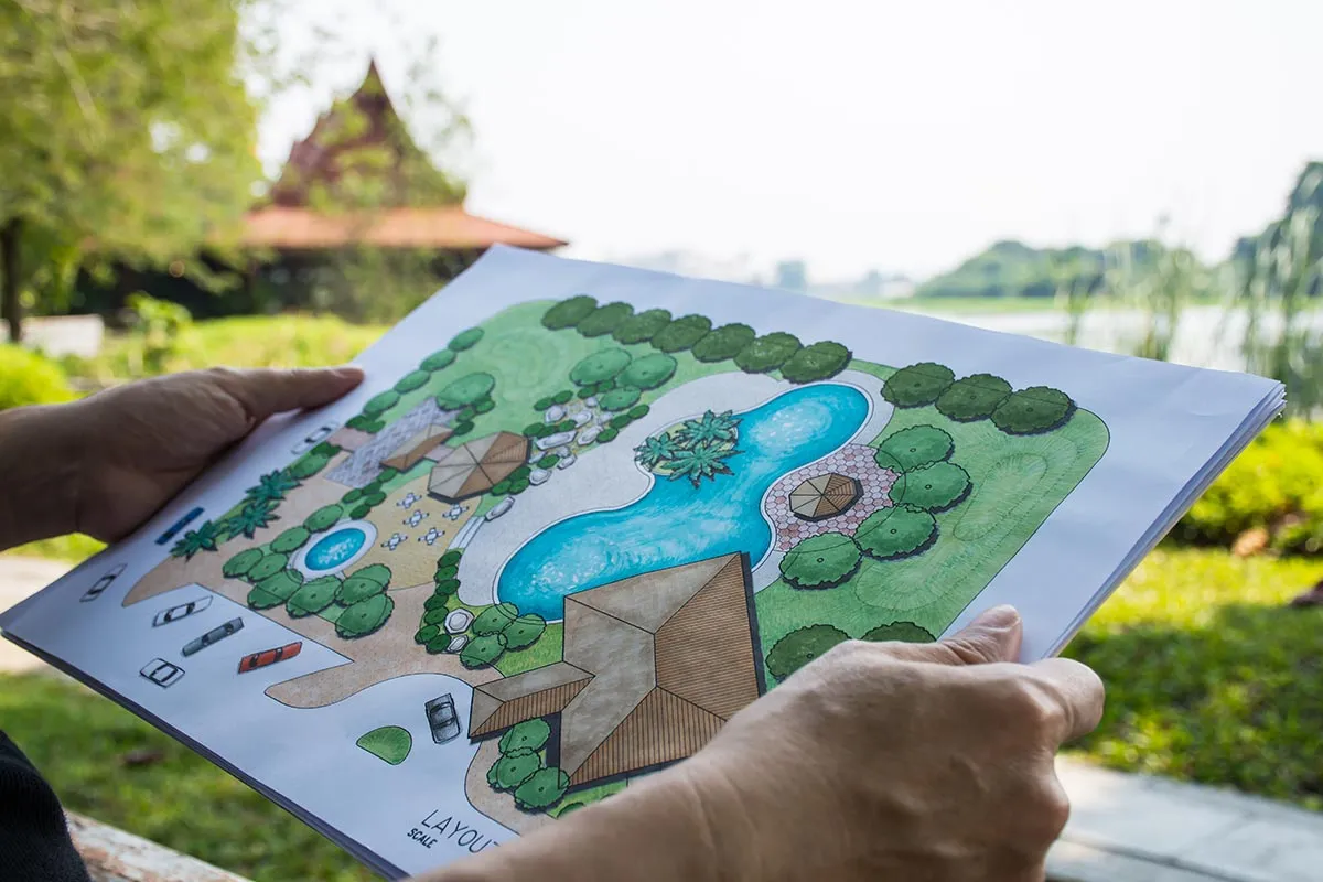 Person schaut auf Gartenplan in Garten