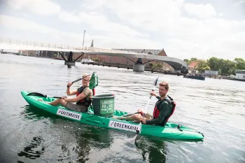 Personen paddeln im Greenkayak auf einem Berliner Kanal und sammeln Müll