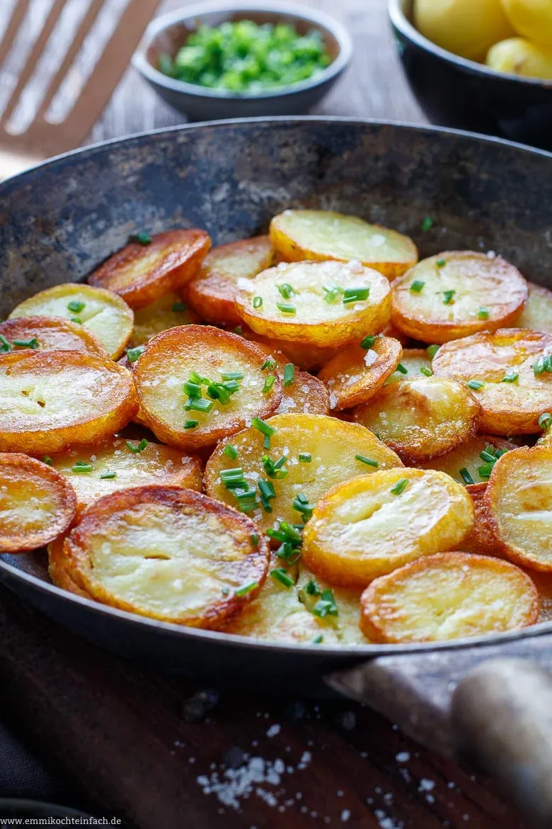 Pfanne mit Butterschmalz und Kartoffelscheiben für knusprige Bratkartoffeln