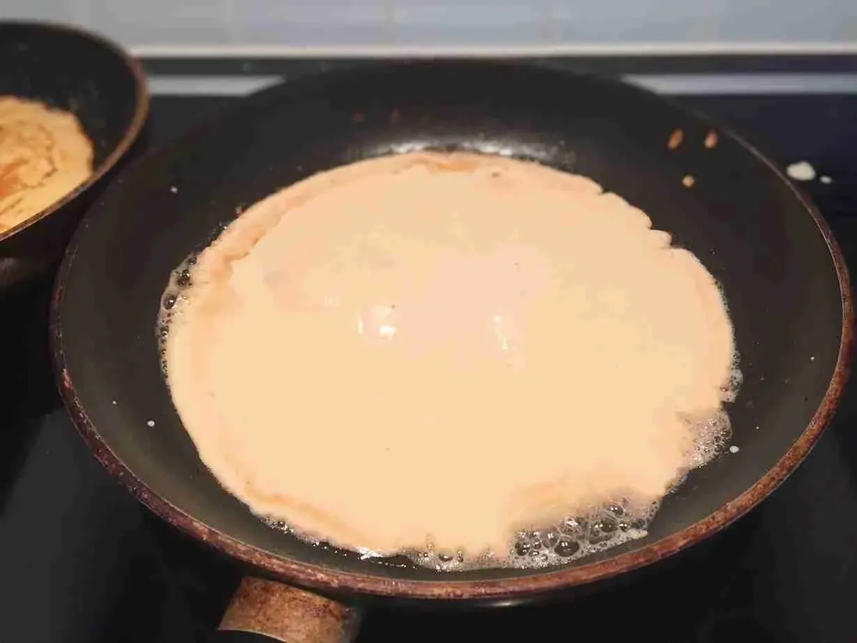 Pfannkuchenteig wird in einer heißen Pfanne goldbraun gebacken.
