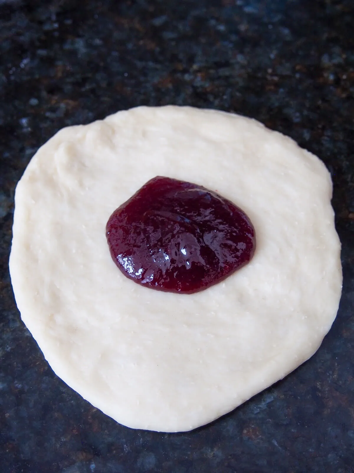 Pflaumenmarmelade auf ausgebreitetem Teig vor dem Verschließen.