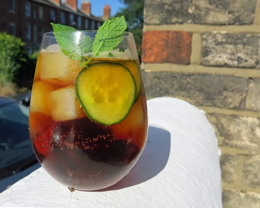 Pimm's Spritz in einem eleganten Glas mit Minze und Gurke, ideal für die Gartenparty