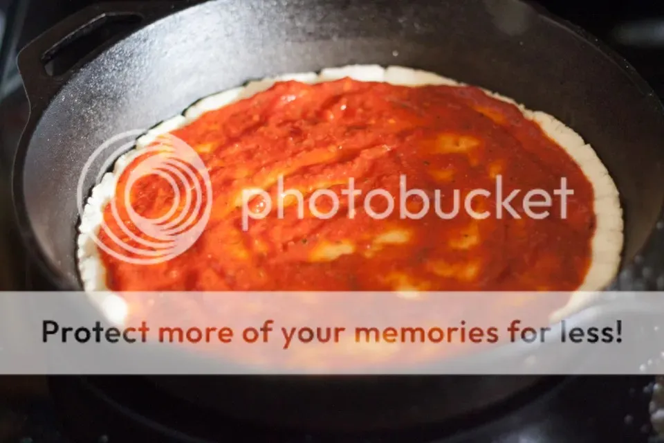 Pizzasoße wird auf den vorgebackenen Teig aufgetragen