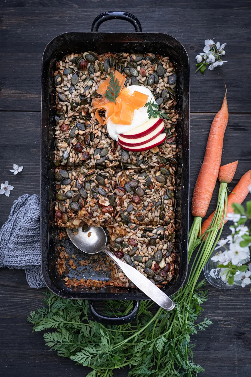 Portion des veganen Carrot Cake Haferflocken-Auflaufs mit Nüssen und Apfelscheiben