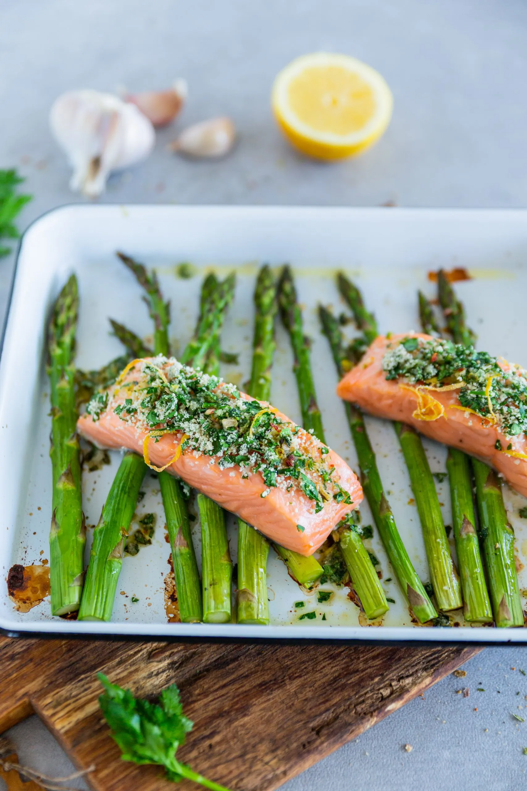 Portion Ofenlachs und Zitronen-Spargel auf einem Teller mit frischen Kräutern