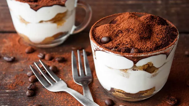 Portioniertes Tiramisu im Glas, garniert mit Kakaopulver und Kaffeebohnen