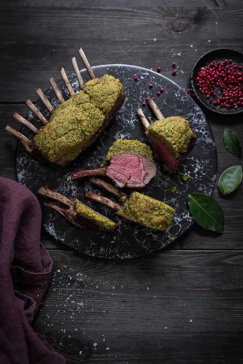 Professionelles Foto eines Lammkarrees mit Pistazienkruste, das die goldbraune Kruste und die saftige Textur des Fleisches zeigt.