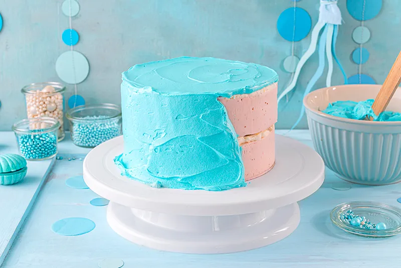 Professionelles Glätten der blauen Schlagcreme an den Seiten der Meerjungfrauen-Torte für eine perfekte Oberfläche