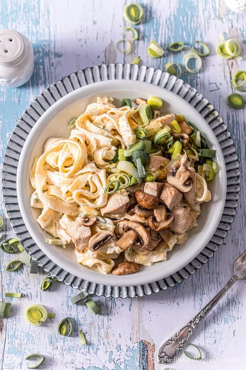 Putenbruststreifen in cremiger Frischkäsesauce mit Lauch und Pilzen, serviert auf Bandnudeln