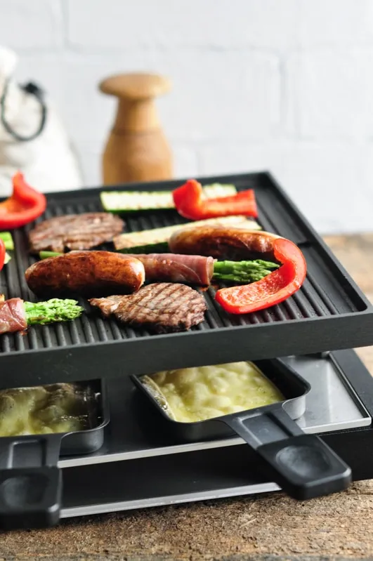 raclette grill mit fleisch gemüse geschmolzenem käse