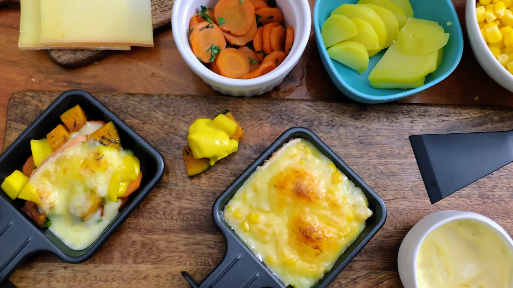 Raclette-Pfännchen mit Kartoffeln, Tomaten und geschmolzenem Schafskäse für vegetarische Genussmomente