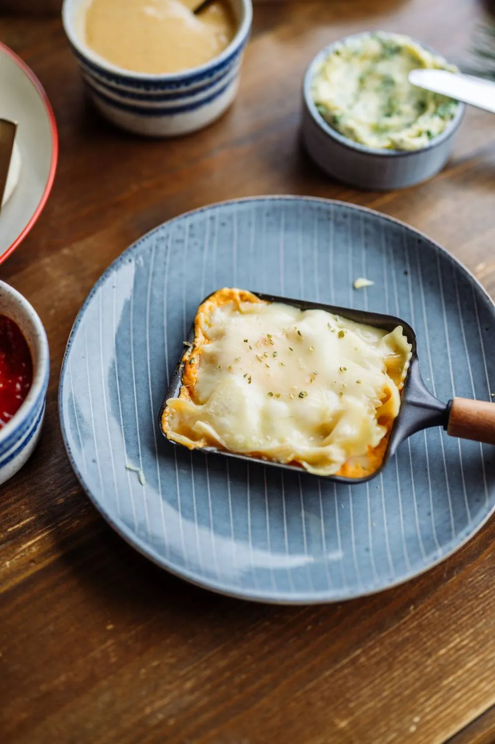 Raclette-Pfännchen mit Pasta und würziger Sauce, bereit zum Überbacken mit Käse