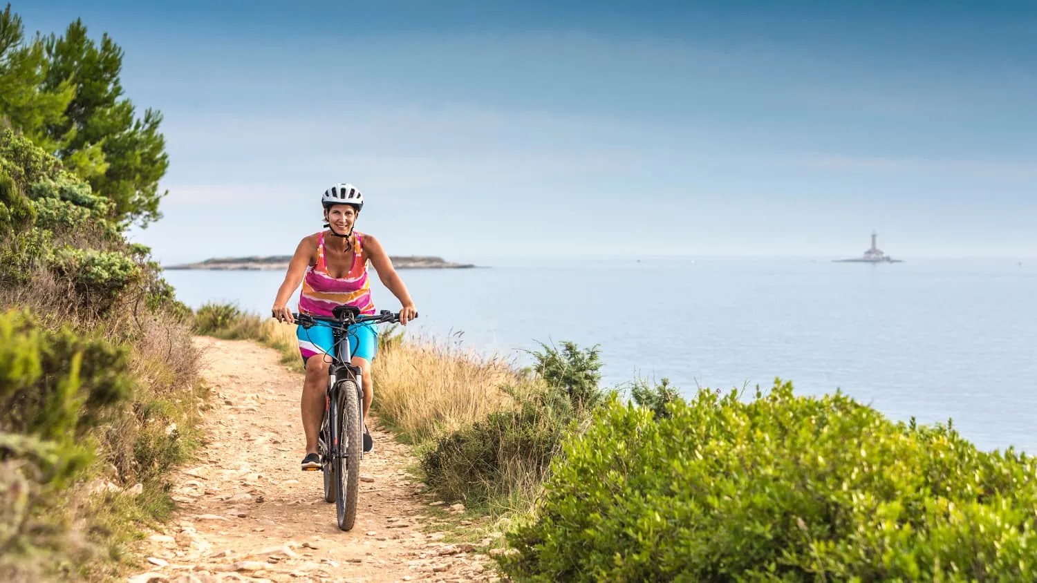 Radfahrerin genießt eine Küstenlandschaft in Kroatien, perfektes Wetter für einen warmen Urlaub im April 2025