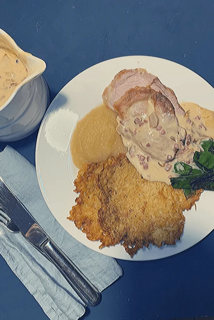 Reibekuchen werden hier mit Schweinebraten, Apfelmus, sautierten Zuckerschoten und einer cremigen Pilz-Speck-Soße serviert.