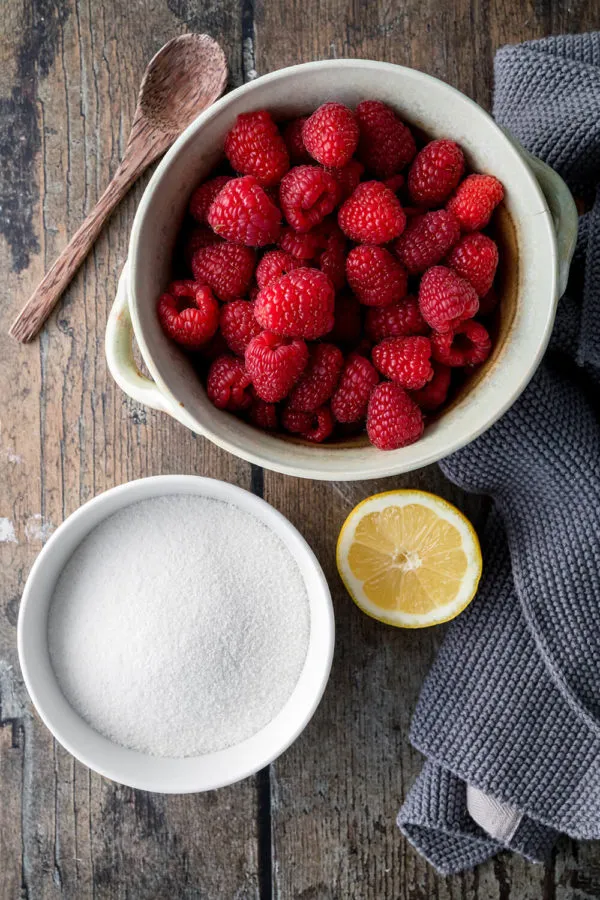 Reife Himbeeren und Gelierzucker, die Schlüsselzutaten für eine köstliche, selbstgemachte Himbeermarmelade.