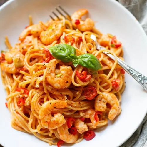 Rezeptbild für schnelle Garnelen Nudeln in Tomaten-Sahnesauce mit frischen Kräutern.