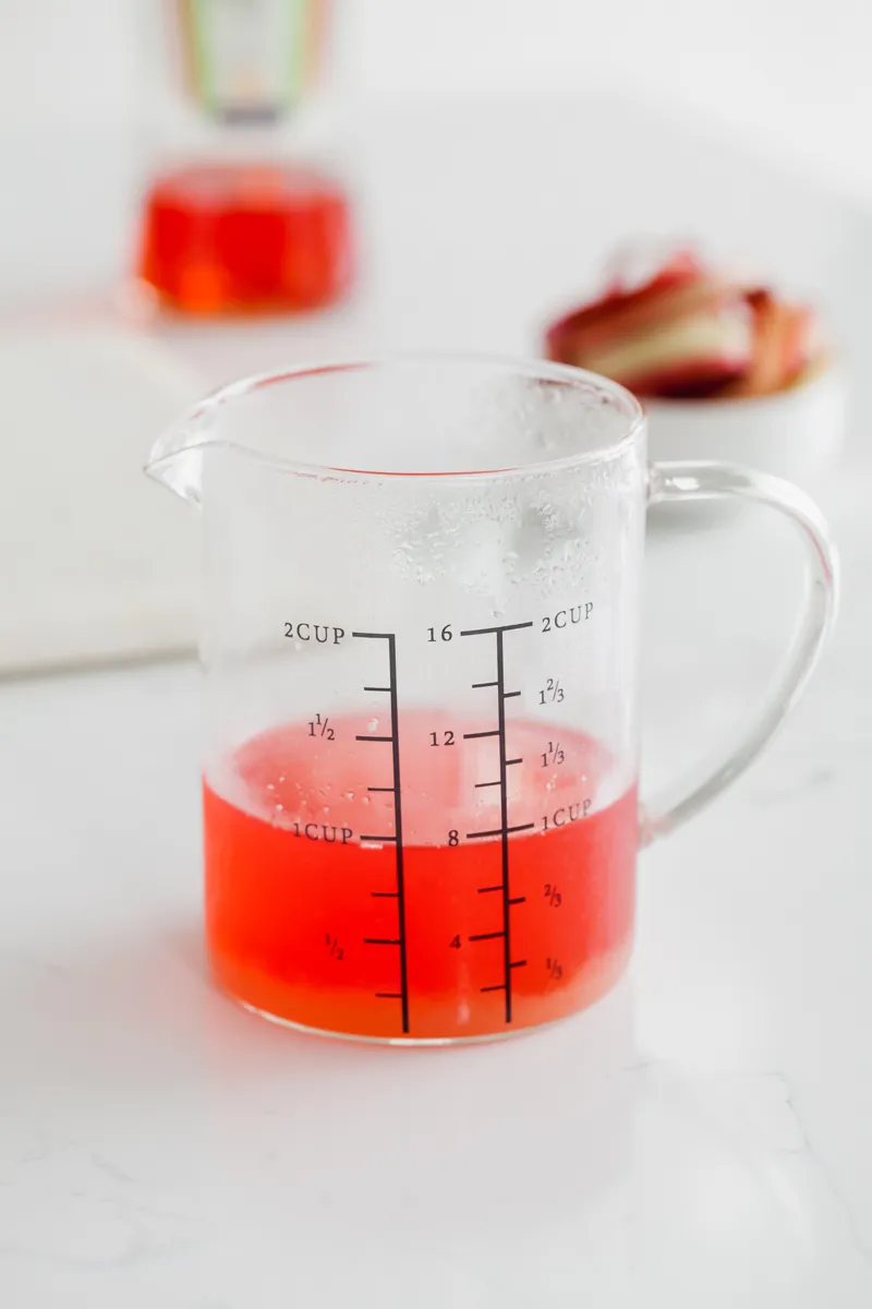 Rhabarber, Zucker und Wasser köcheln in einem Topf zur Herstellung von Rhabarbersirup.