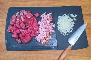 Rindfleisch, Speck und Zwiebeln in Würfel schneiden.