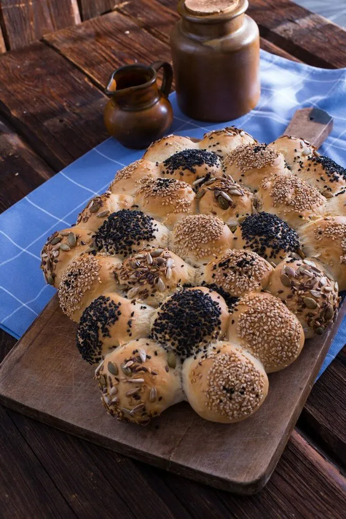 Rohe, aufgegangene Wagenrad Brötchen mit verschiedenen Saaten bestreut, bereit zum Backen im Ofen.
