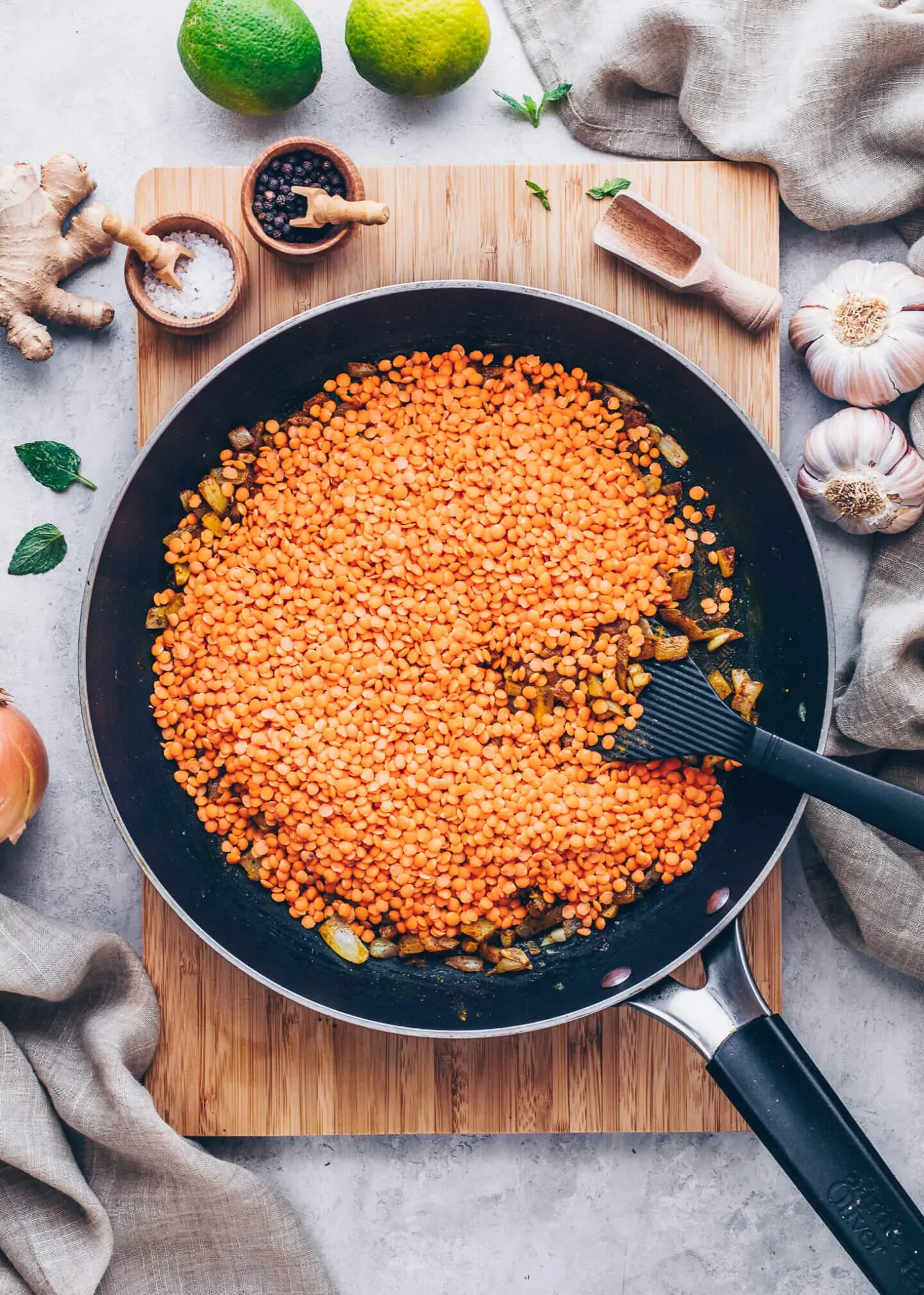 Rote Linsen werden zur Zwiebel-Gewürz-Mischung in die Pfanne gegeben, ein wichtiger Schritt für veganen Linsen-Dal.