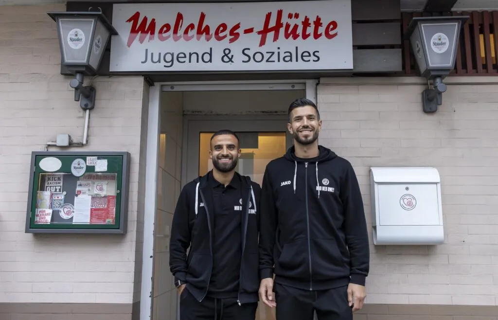 RWE-Profis Ramien Safi und Klaus Gjasula im Gespräch mit Fans beim Hüttenabend des AWO-Fanprojekts.