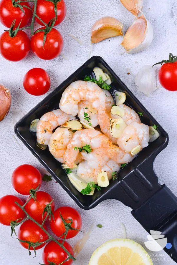 Saftige Garnelen im Raclette Pfännchen, angebraten mit frischem Knoblauch und einem Schuss Weißwein, eine elegante Raclette Idee für Meeresfrüchte-Liebhaber.