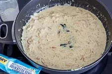 Sahne, Crème fraîche und Senf werden in der Pfanne verrührt, um die cremige Basis für den Spinat im Lachs Auflauf zu schaffen.