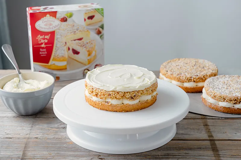 Sahnefüllung gleichmäßig auf die erste Schicht des Geburtstagskuchens auftragen