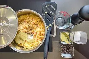 Sauerkraut mit Brühe, Lorbeerblättern und Wacholderbeeren im Topf schmoren lassen, für den vollen Geschmack beim Kochen