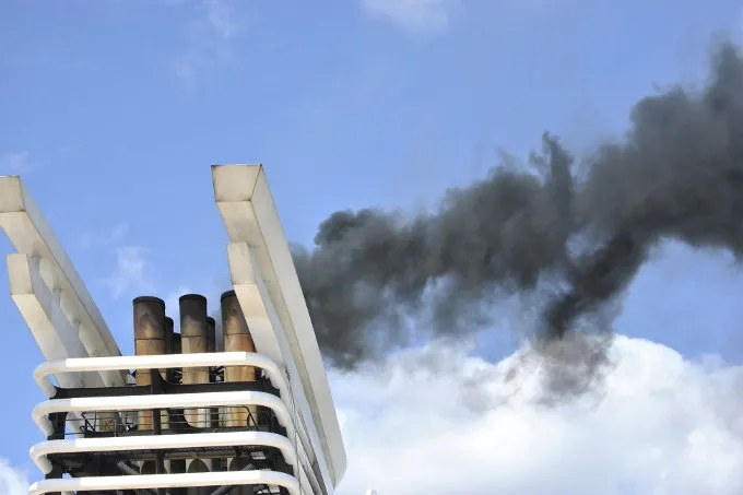 Schiffsschornstein mit Auspuffgasen vor blauem Himmel