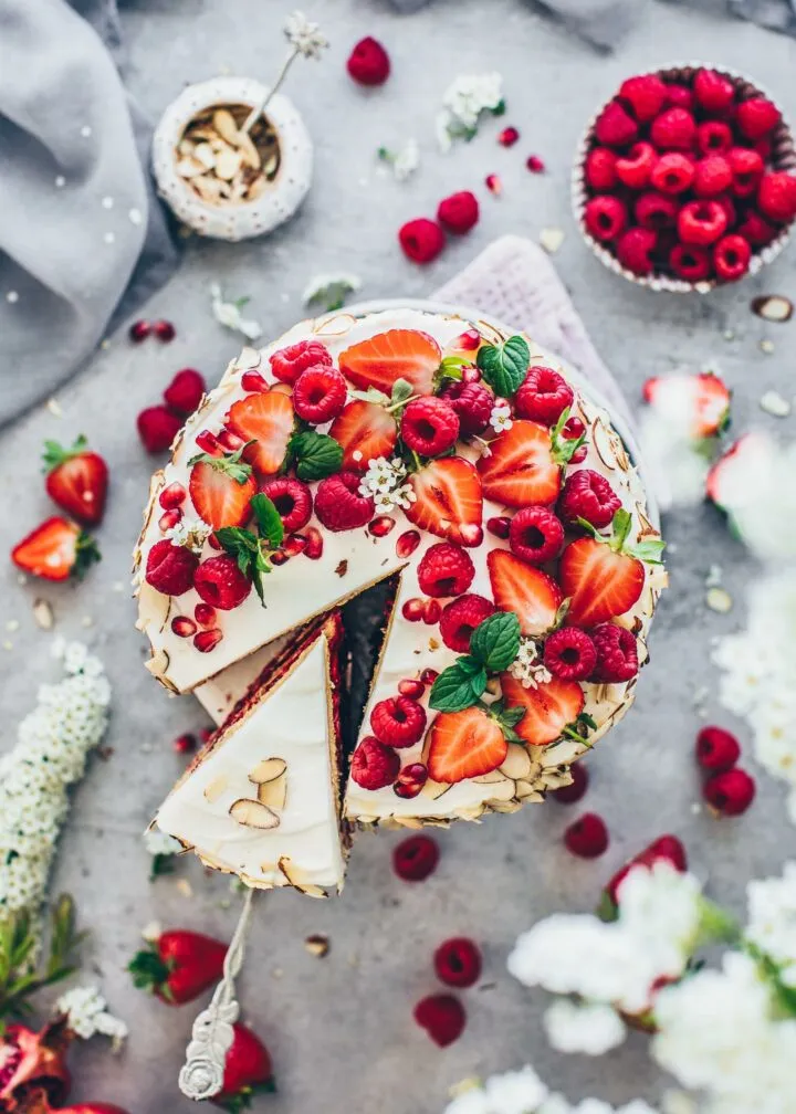 Schnittbild einer geschichteten veganen Himbeer-Sahnetorte mit cremiger Füllung und Beeren.