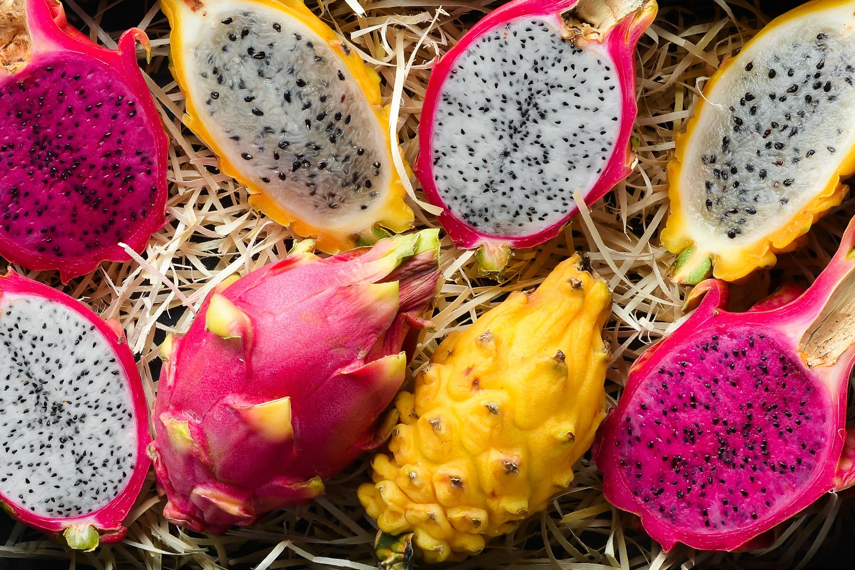 Schnittbilder von gelben und pinken Drachenfrüchten zusammen mit einem Glas Drachenfruchtsaft, der ihre Farbenpracht hervorhebt.