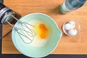 Schritt 2: Eier und Mineralwasser werden dem Teig zugegeben und gut verrührt, um einen fluffigen Pfannkuchenteig zu erhalten.