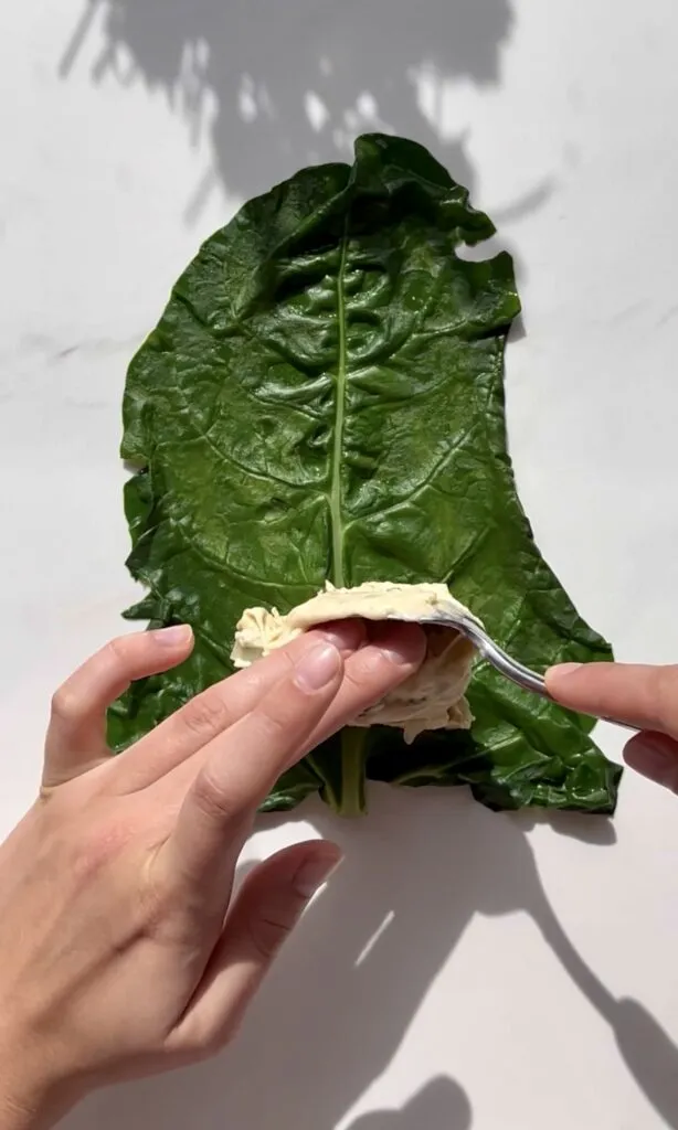 Schritt-für-Schritt-Anleitung: Eine Capuns-Teigtasche wird in ein blanchiertes Mangoldblatt gewickelt.