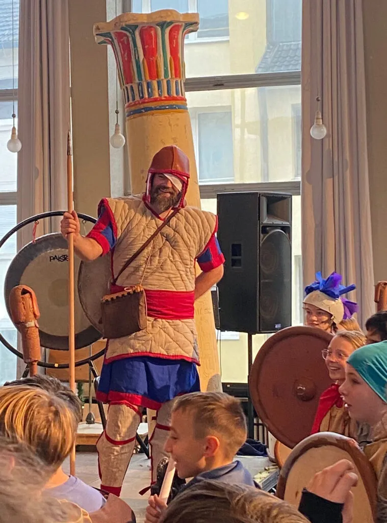 Schülerinnen und Schüler in antiken Kostümen diskutieren im Schulflur