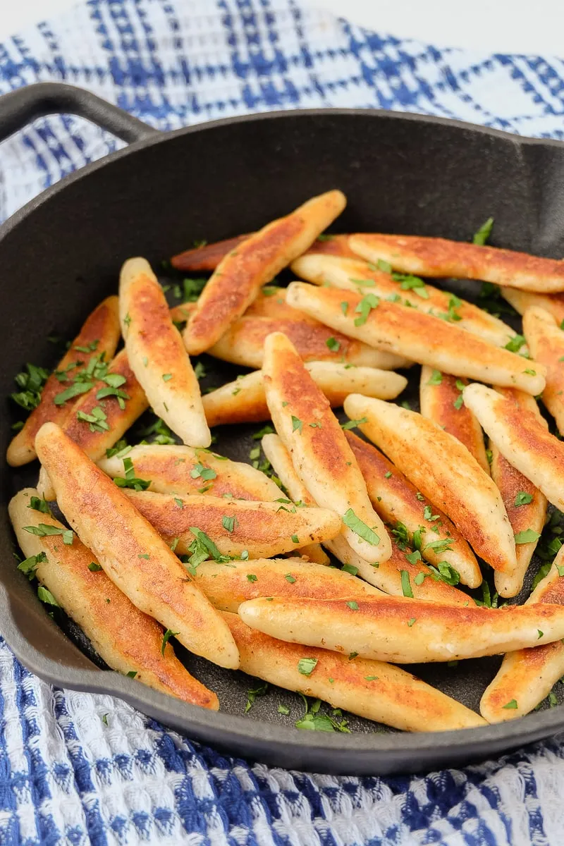 Schupfnudeln in einer gusseisernen Pfanne, mit einem Handtuch darunter