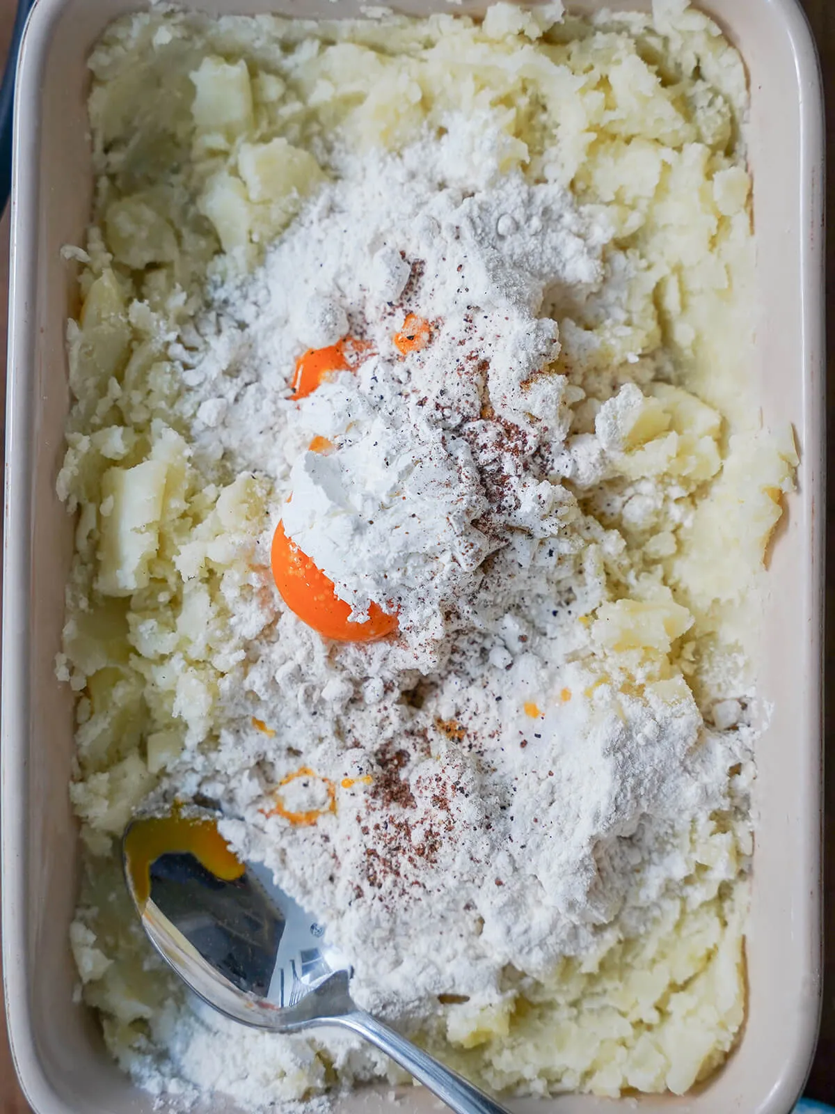 Schüssel mit Kartoffelpüree, Eigelb, Mehl und etwas Gewürzen darauf.