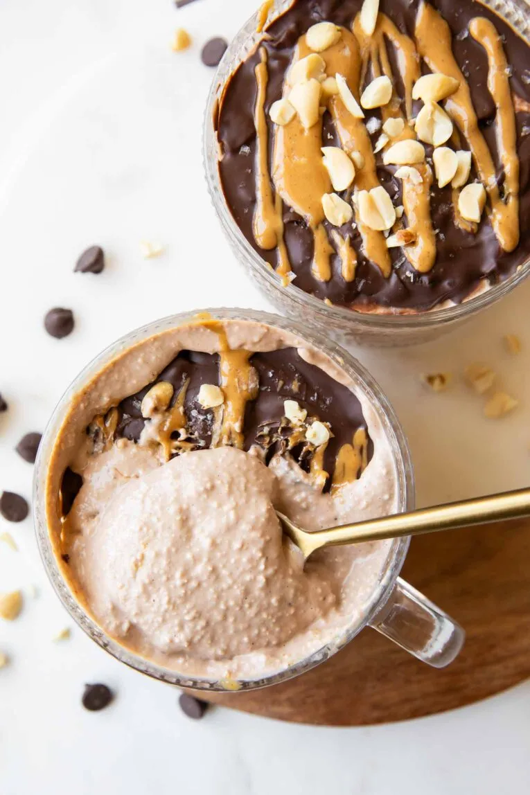 Schüssel mit Snickers Overnight Oats, aus der eine Löffel herausgenommen wird.